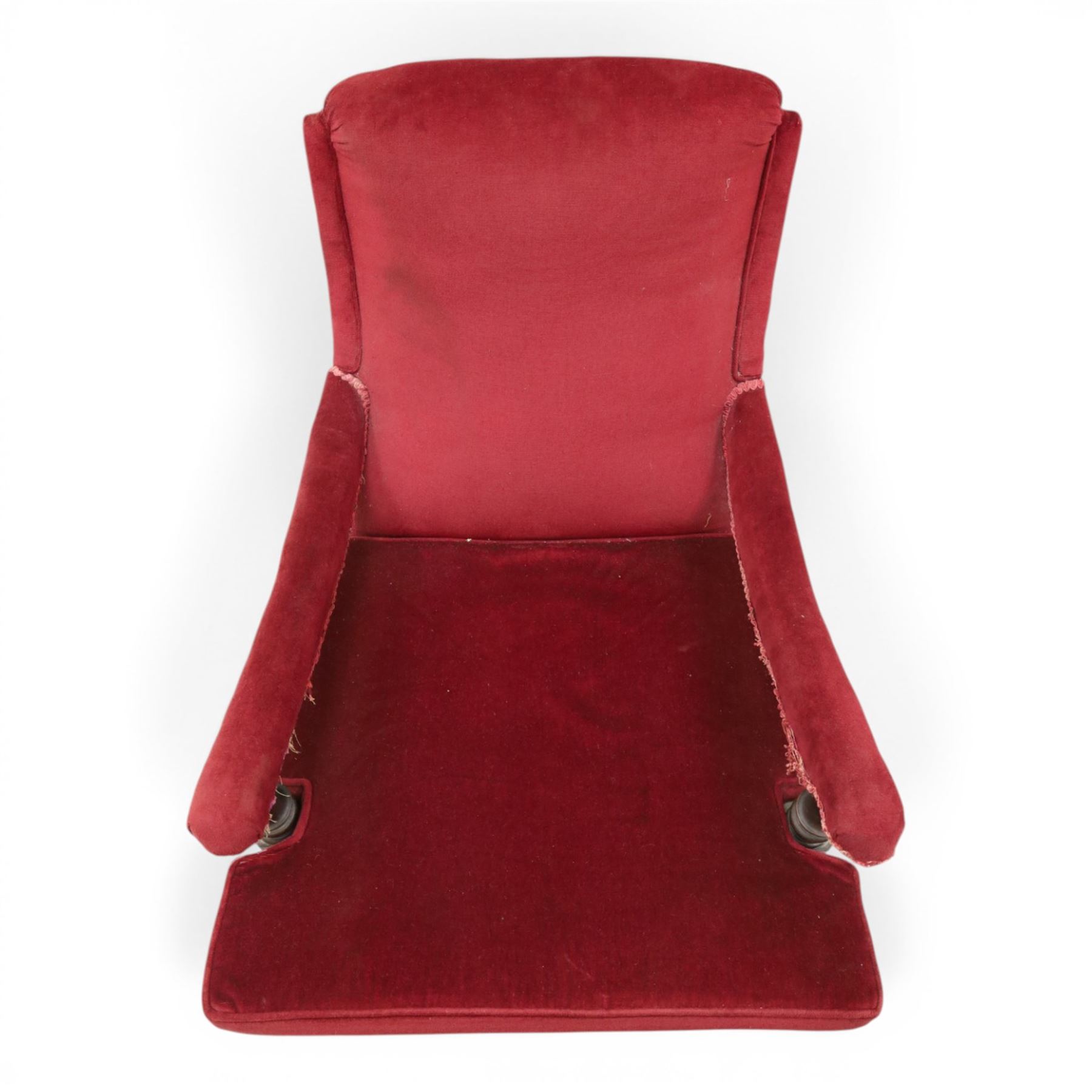 Victorian walnut framed reading open armchair of reclined position, the high sprung back and deep seat upholstered in crimson fabric with matching loose seat cushion, turned arm terminals over turned feet terminating to brass castors