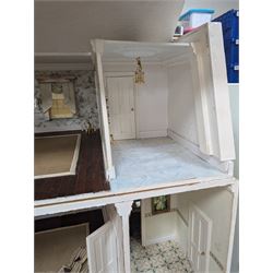 Two modern three storey dolls houses, each painted green with decorated interiors, both upon a single white wooden base, together with a large collection of dolls house furniture, accessories and figures 