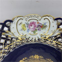Meissen style pedestal dish, with central panel depicting a trading scene in a harbour setting, the bowl with openwork lattice sides divided by three hand painted floral panels, upon a blue ground with gilt detailing, upon a fluted knopped pedestal and circular foot, H22cm