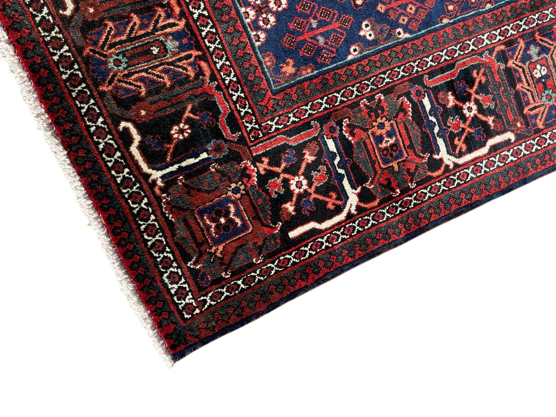 Persian Joshaghan crimson ground rug, stepped lozenge medallion surrounded by repeating foliate lozenge motifs, the border decorated with stylised plant motifs, within geometric guard stripes