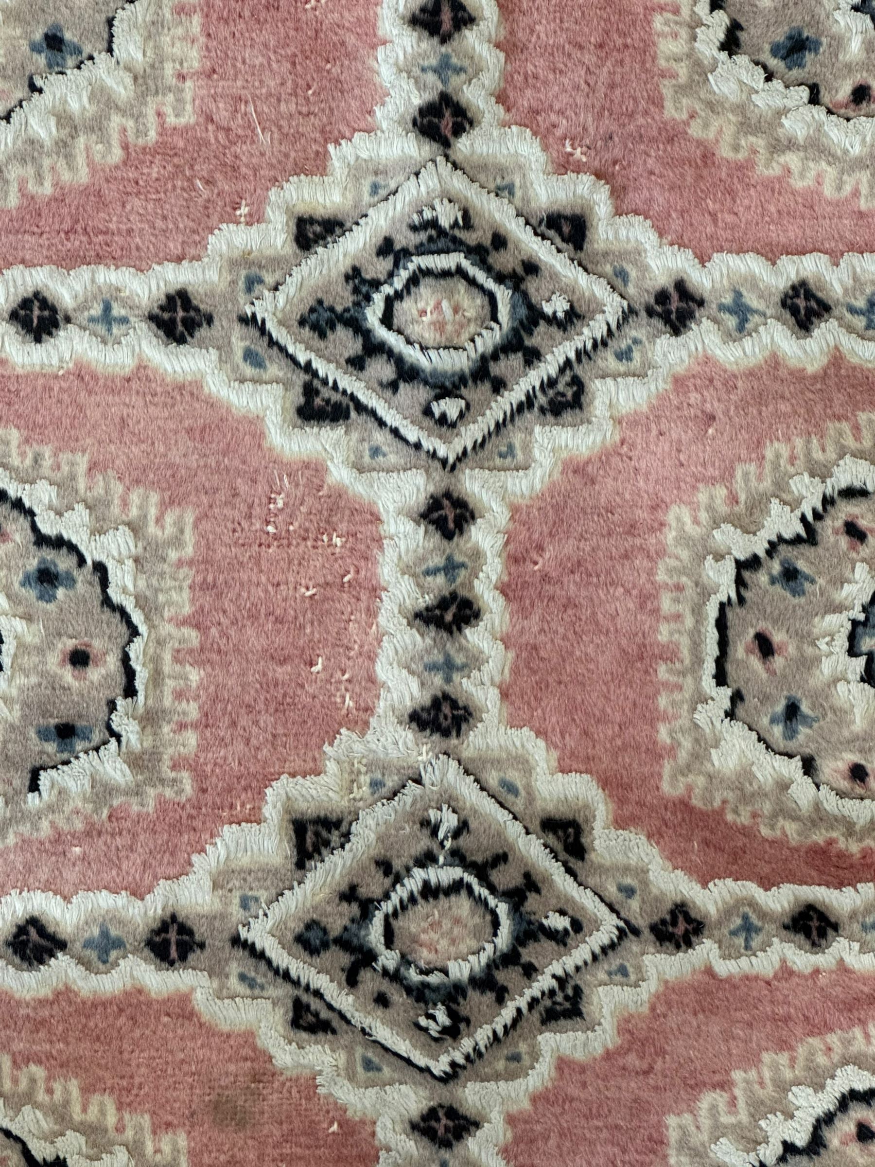 Persian design pale pink ground rug, the field divided into panels and decorated with Gul motifs, wide multi-band border with geometric patterns 