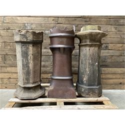 Collection of three Victorian and early 20th century reclaimed terracotta chimney pots, comprising: one cylindrical form with weathered, cracked glaze and flared octagonal base; one deep red cylindrical pot with fluted midsection and castellated rim, bearing moulded number ‘25’; and one tapering hexagonal example with wide flared rim and weathered patina. All with age-related wear and chips, consistent with use and outdoor exposure. Plus a selection of cast stone pieces including fountain 