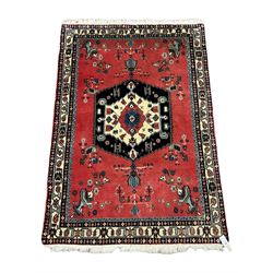 Persian red ground rug, the field decorated with medallion and stylised flower heads, four band border with repeating design