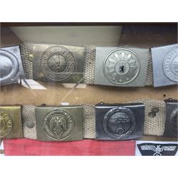 Display of eleven German belt buckles including 'SS', Party Buckle, two Army, Fire Service, two Luftwaffe, NSKK, Hitler Youth and WW1 Army; framed with three cloth badges and an armband