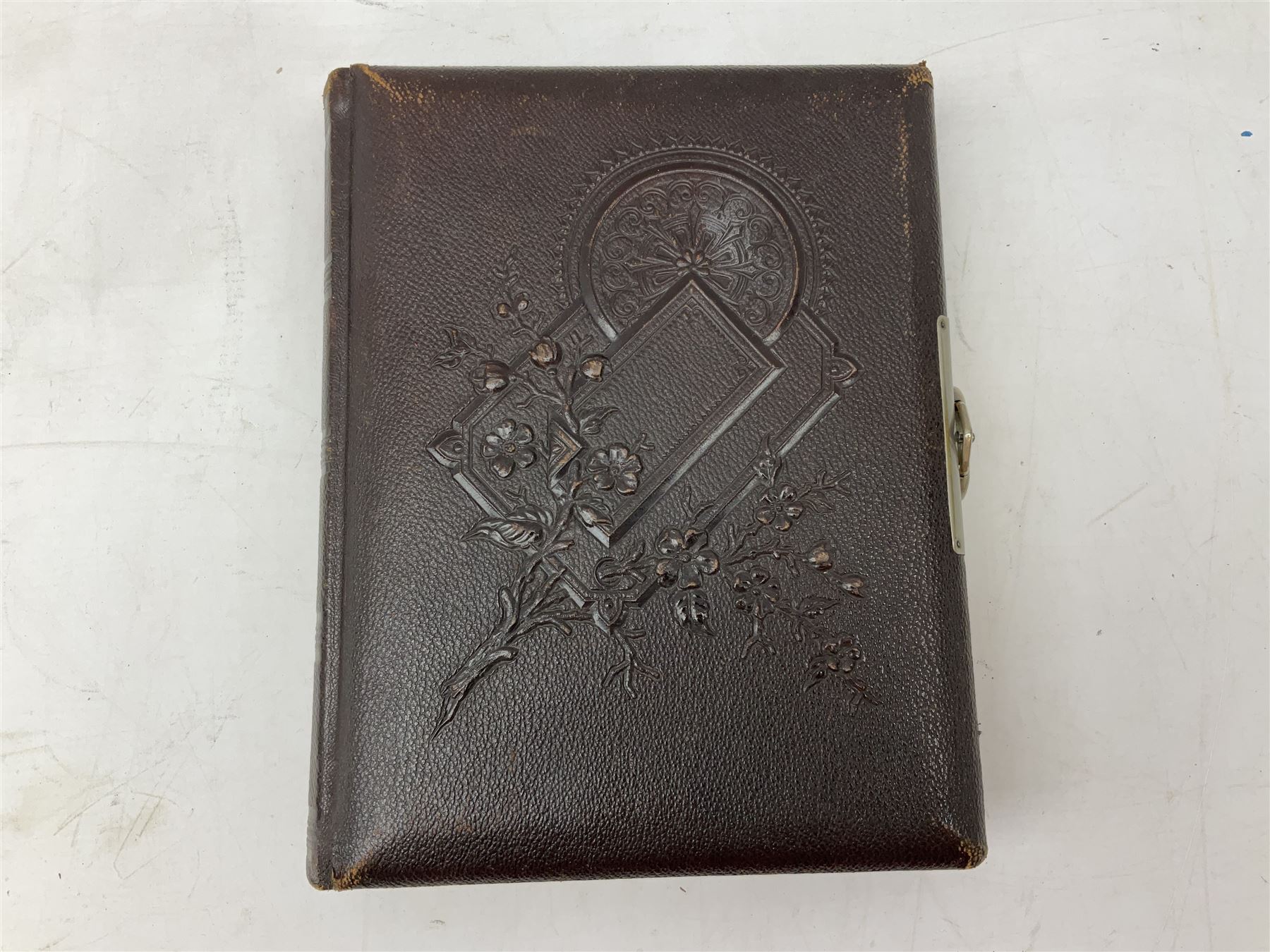 Victorian leather bound photo album, the interior leaves containing apertures of various sizes and shapes of portraits surrounded by printed floral designs, H28cm