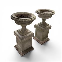 Pair of weathered cast stone Neoclassical design garden Kylix shape urns, foliate moulded rim over a gadrooned underbelly, the scalloped socle over a rectangular pedestal with faux-panelled sides, stamped with stylised ‘H’ monogram
