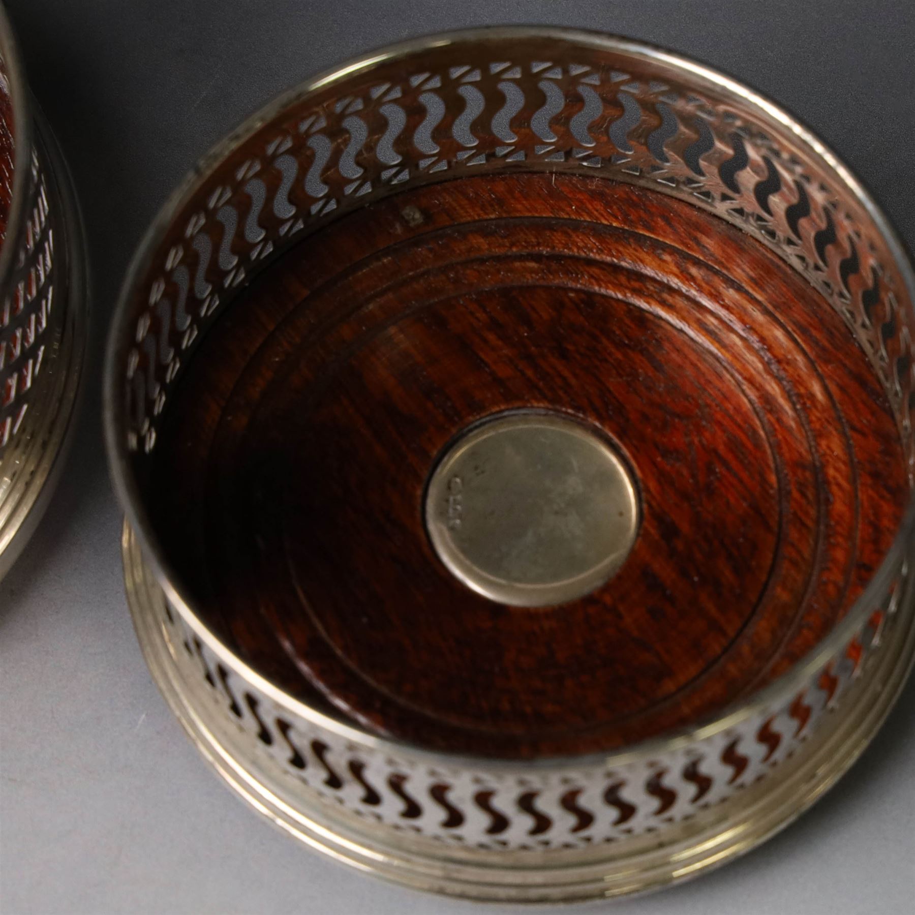 Two silver mounted bottle coasters, the larger example with latticework sides, hallmarked Mappin & Webb Ltd, Birmingham 1993, the smaller example with pierced sides, hallmarked W I Broadway & Co, Birmingham 1998, largest D12cm