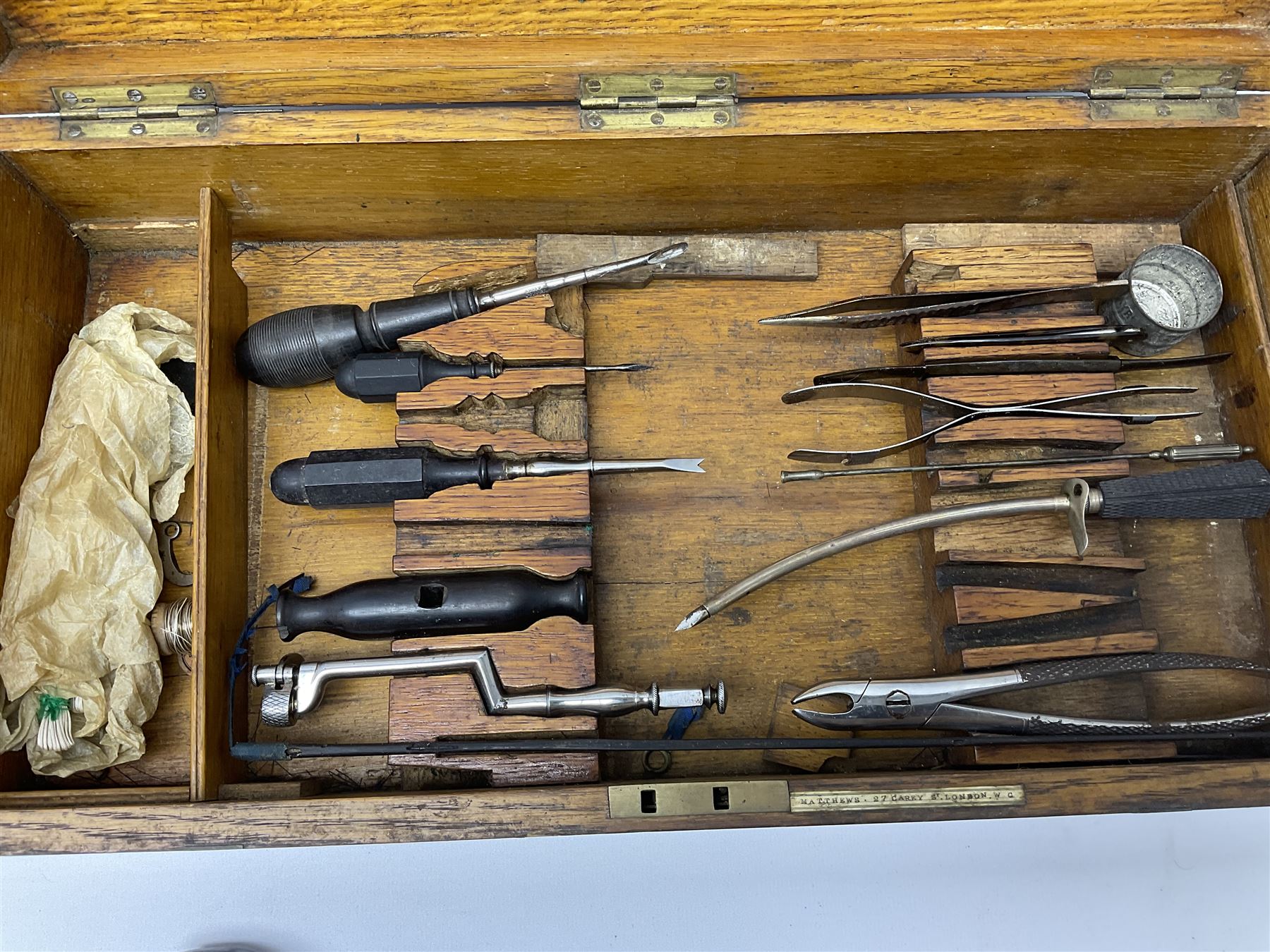 Naval doctor's surgical instruments, contained in a converted brass bound oak pistol box, the hinged lid opening to reveal two removable fitted trays, containing 19th century and later saws, scalpels, tweezers etc