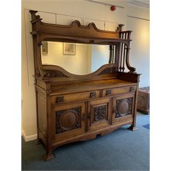 Late 19th century Arts & Crafts period oak mirror back sideboard, shaped bevelled mirror back carved with foliate scrolls and flower heads, down swept supports with elongated club-shaped uprights, moulded rectangular top over two drawers and three cupboards, the drawer fronts with copper handles decorated with sailing ships, panelled doors carved with mythical beasts, flowerheads and foliage, on moulded block feet