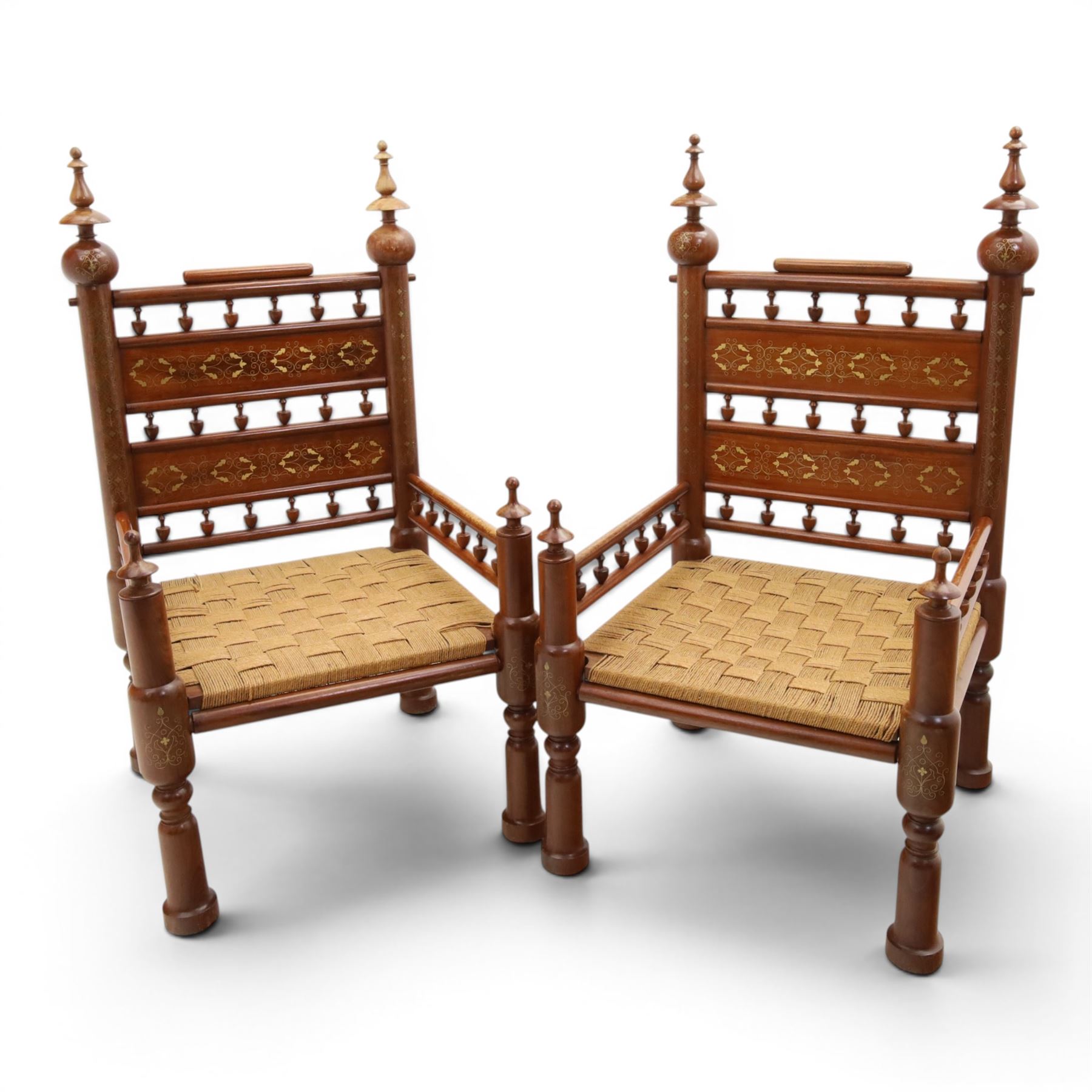 Pair of Anglo-Indian brass inlaid hardwood low chairs, the backs with turned spindle rails and rectangular panels inlaid with scrolling foliate decoration, woven rush seats within moulded frames, raised on turned supports with ring turned feet