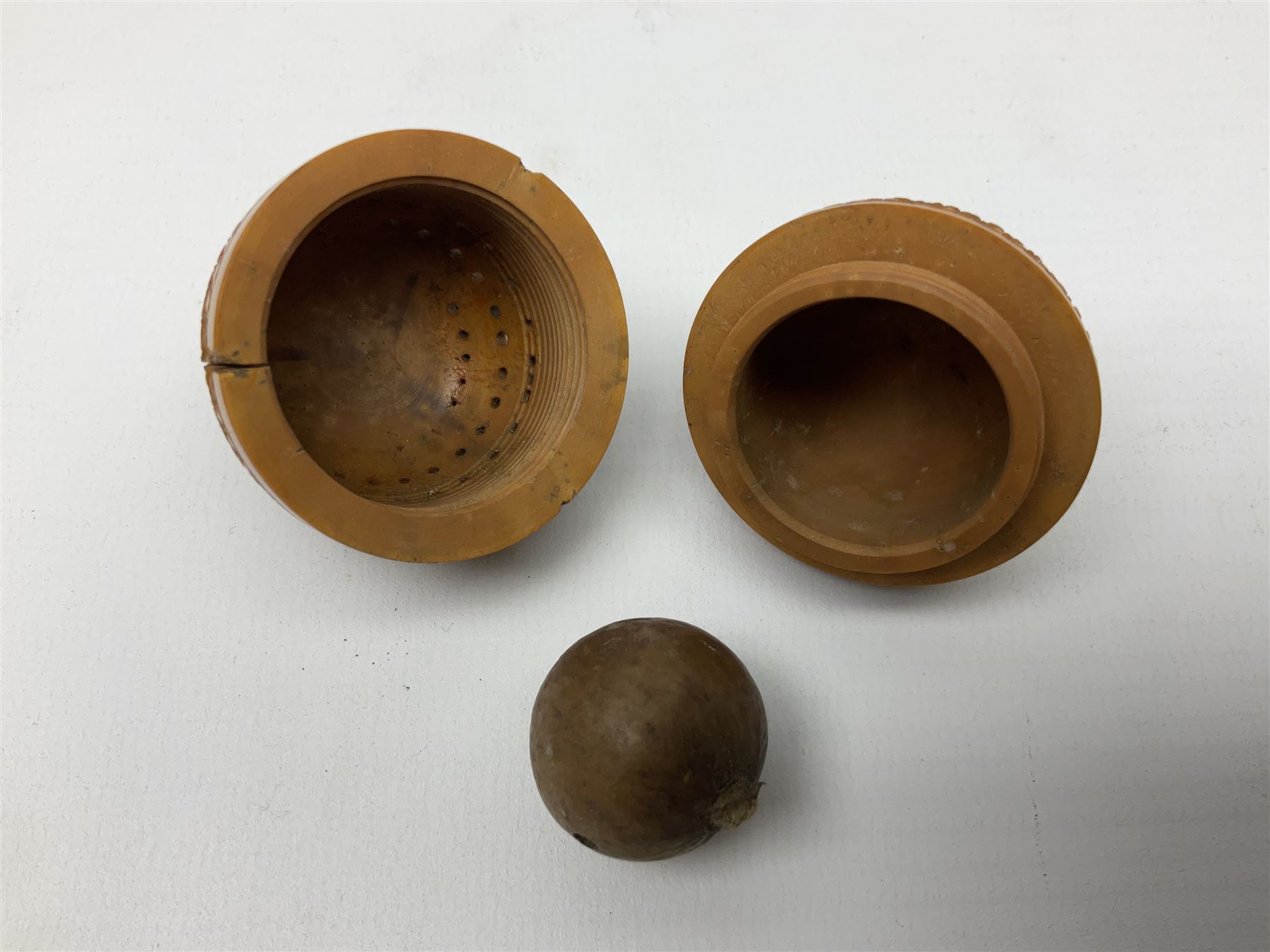 Three 19th century coquilla nut pomanders or flea catchers, each of egg shaped form with carved and pierced decoration and screw threaded join, largest example 6cm
