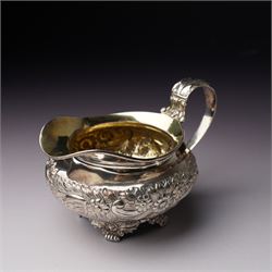 Matched three piece silver tea set comprising teapot of squat circular form London 1827,  milk jug of similar date and sugar bowl with Britannia standard marks, all with later embossed floral decoration and coat of arms, all marks rubbed