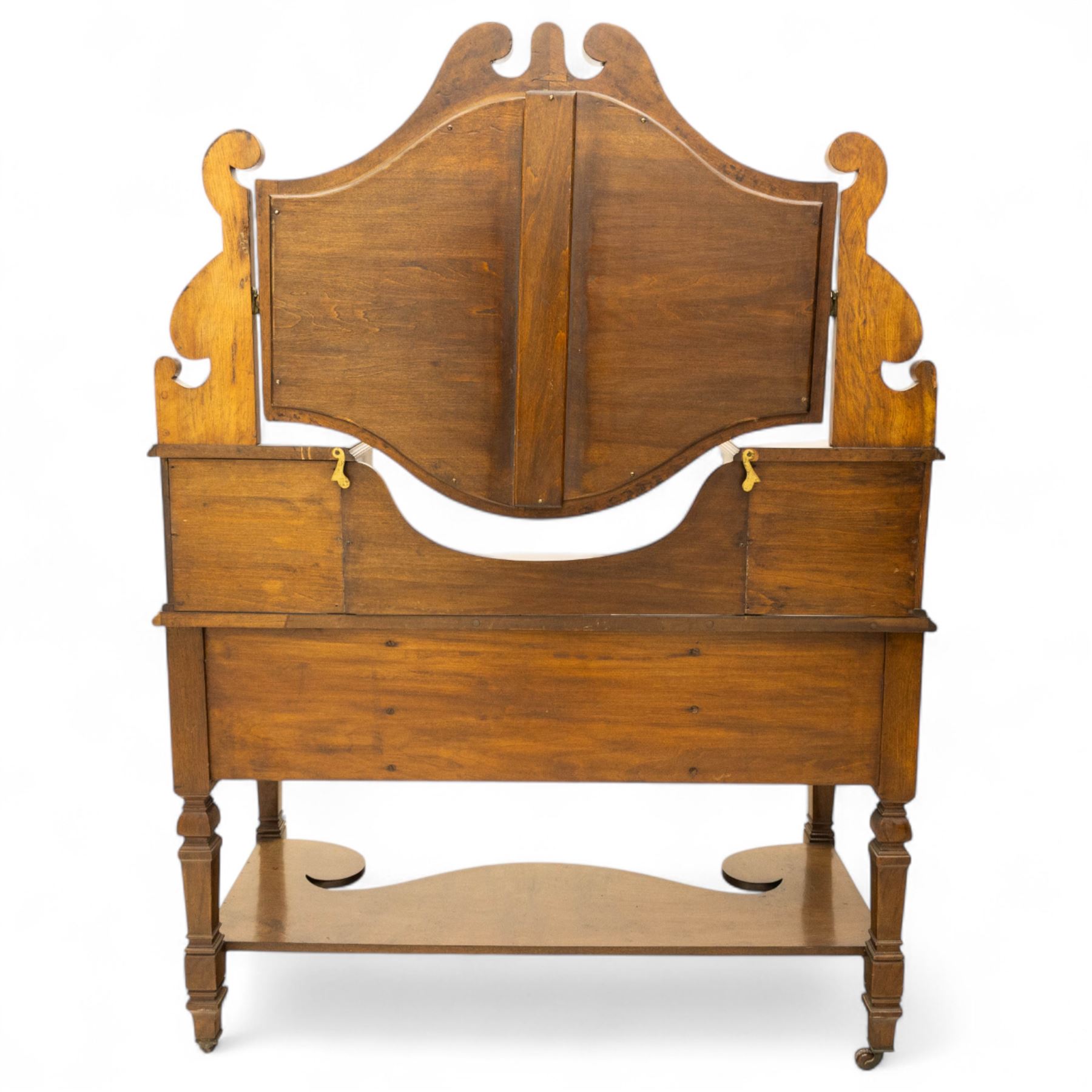 Late Victorian burr walnut veneer dressing table, the arched swing mirror surmounted by pierced scroll cresting, flanked by twin drawers on turned columns, over moulded rectangular top with five drawer arrangement, on block supports with shaped undertier