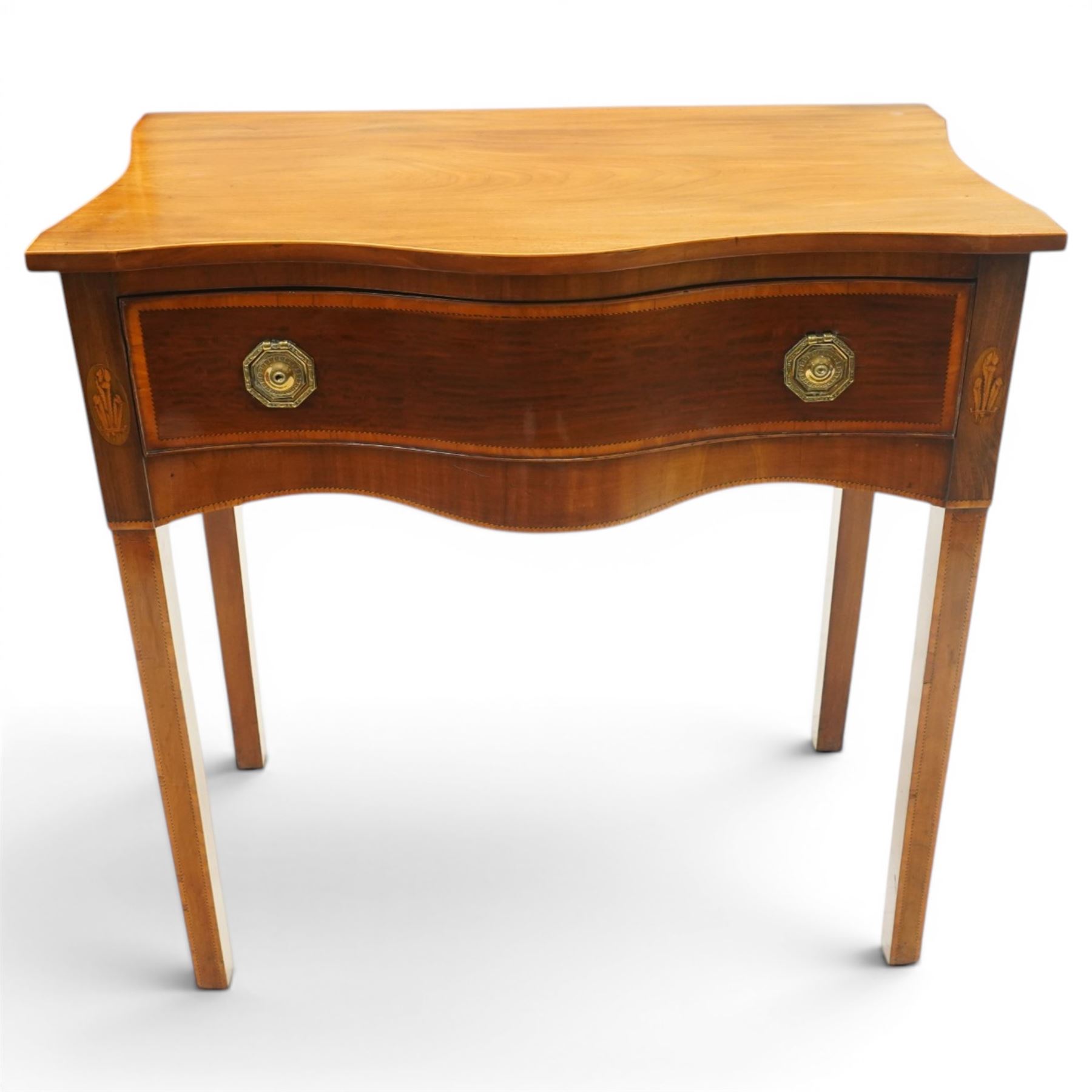 Ealy 19th century Sheraton design inlaid mahogany serpentine-fronted side table, shaped rectangular top with boxwood-inlaid edge, fitted with singe cock-beaded frieze drawer with satinwood cross-banding and herringbone stringing, fitted with original pressed brass octagonal handle plates, flanked by oval feather motif inlays, raised on square tapering supports