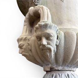 Cast stone classic garden urn, the rim decorated with leaves and berries, twin handles with face masks, raised on square base, stamped HGC