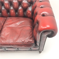  Three seat Chesterfield settee, upholstered in deep buttoned oxblood leather, turned supports on castors, W180cm  