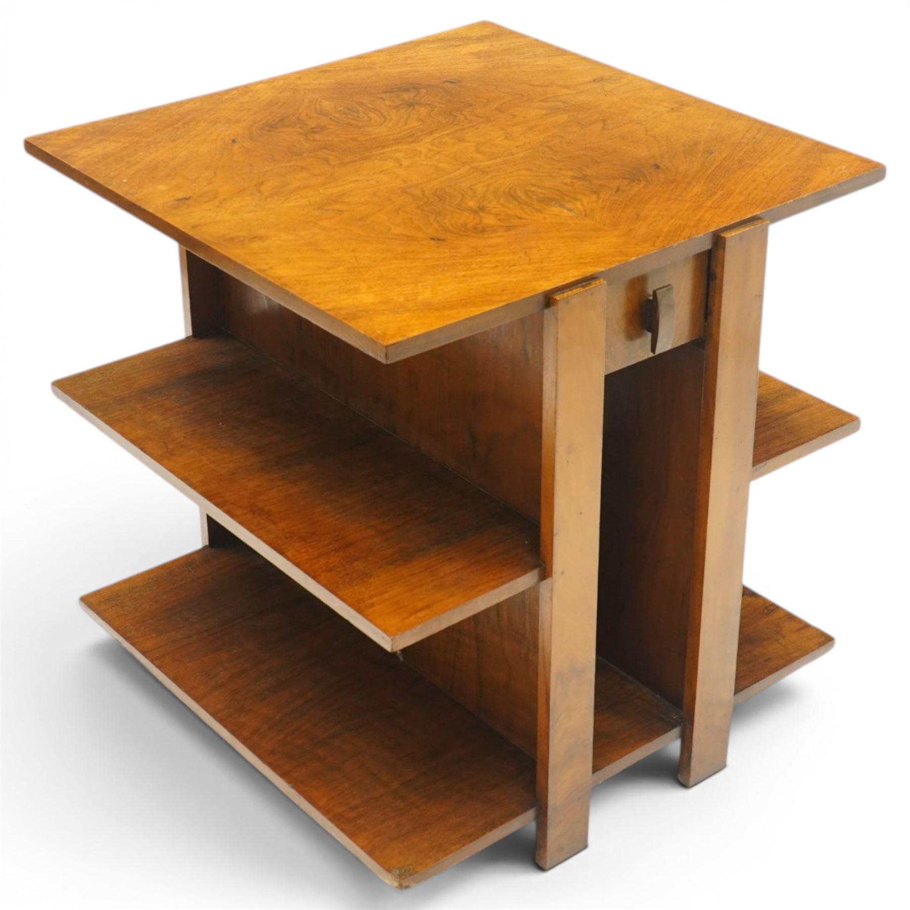 Art Deco walnut coffee table, square book-matched veneered top over single frieze drawer with brass handle, flanked by open side shelves, raised on rectangular end supports