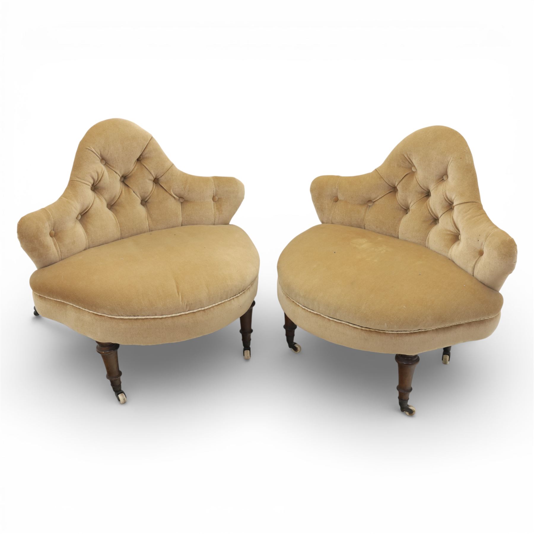 20th century pair of bedroom chairs upholstered in buttoned taupe velour, each of slipper chair form with low wraparound back and deep seat, the backs button tufted with padded wings, raised on turned front supports with castors