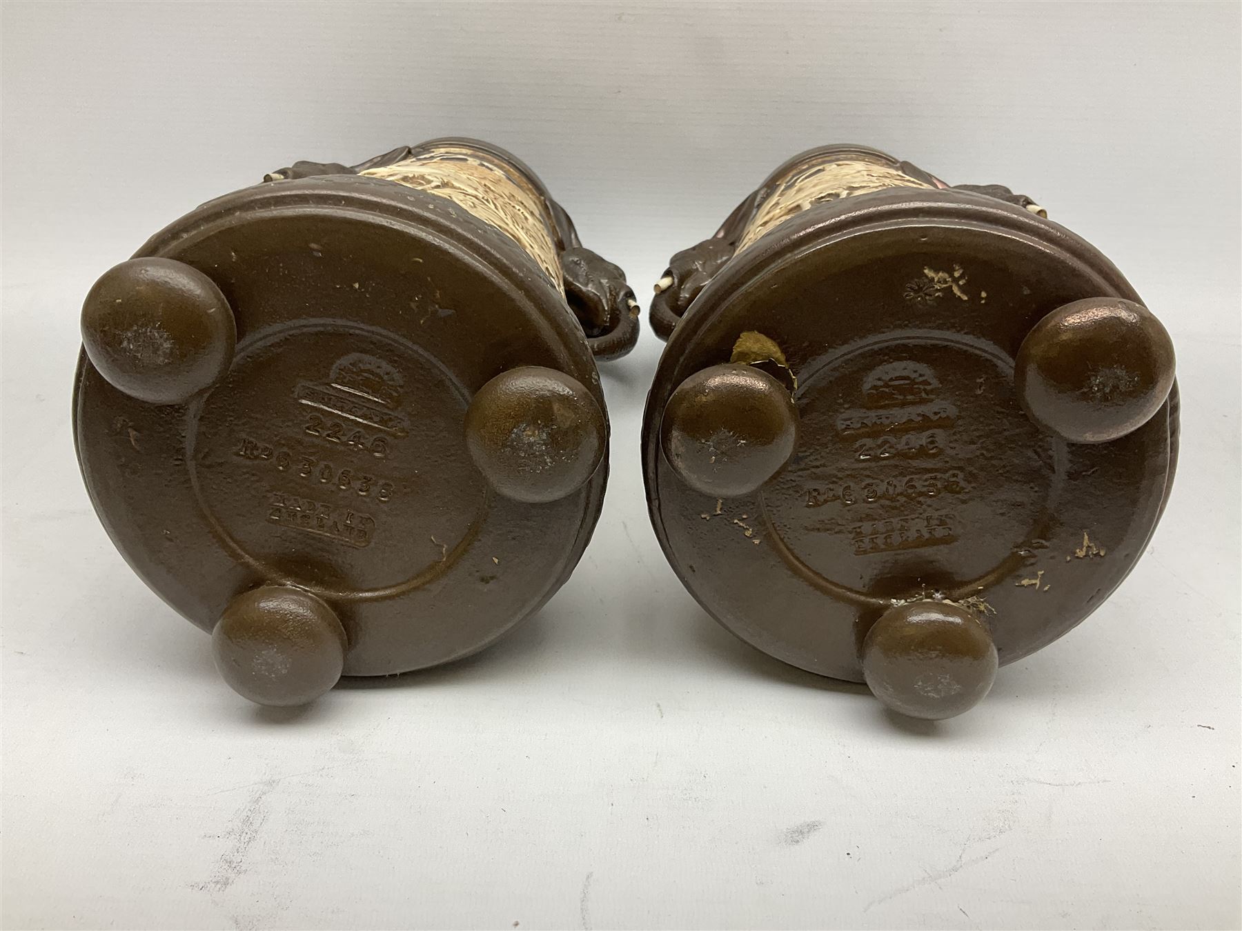 Pair of Bretby vases of tapering cylindrical form decorated with elephants, cranes and fishermen, the bodies with twin elephant mask handles, with coppered borders, raised upon three bun feet, stamped Bretby 2246 marks beneath, H32cm