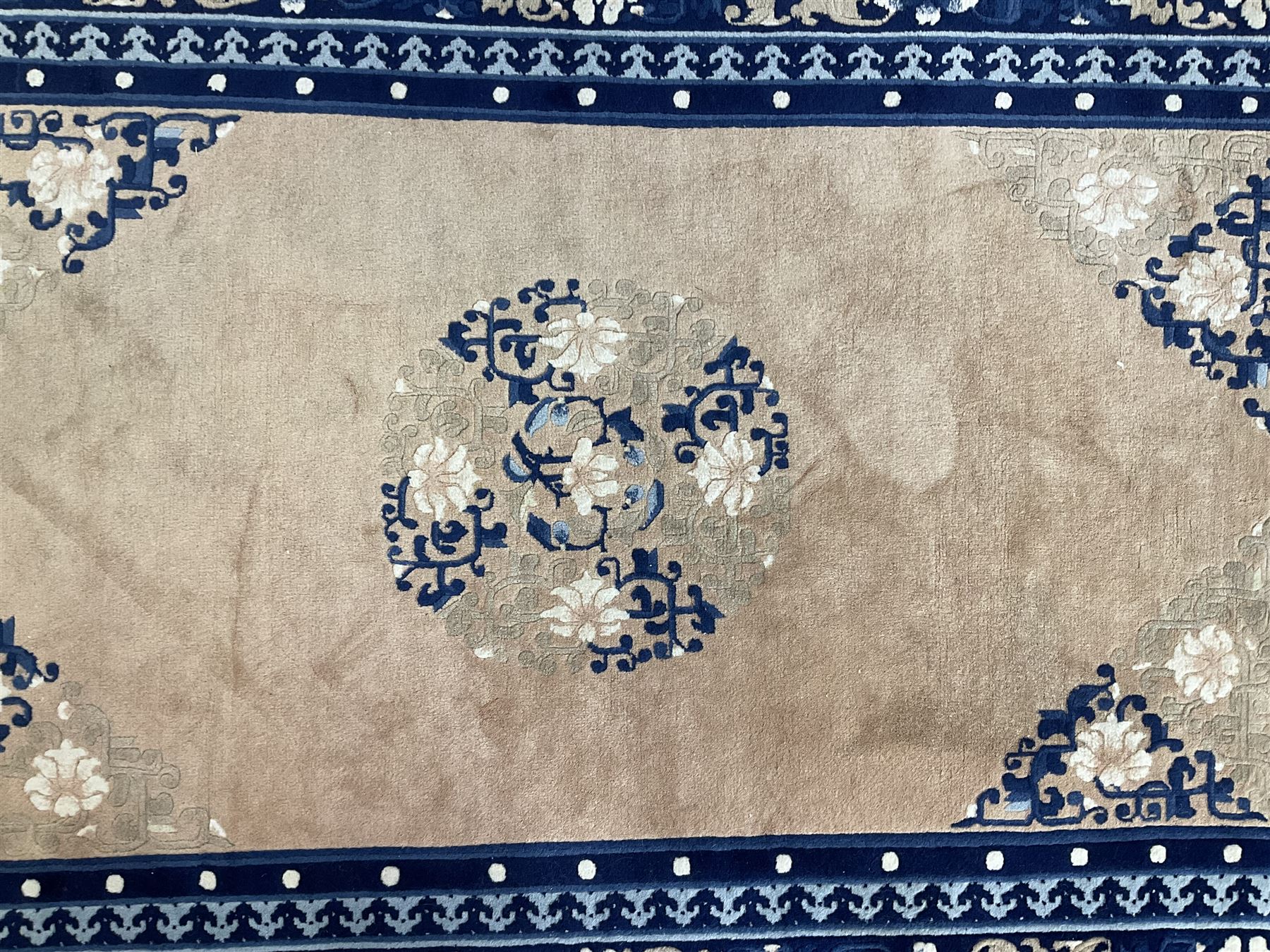 Chinese washed woollen peach ground rug, indigo borders and trailing foliate decoration, central medallion decorated with flowerheads 