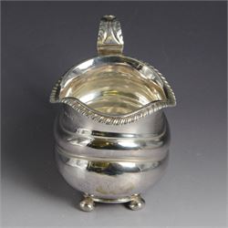 George III silver milk jug, of oval form with oblique gadrooned rim and acanthus leaf capped handle, upon four bun feet, hallmarked London 1819, maker's mark worn and indistinct, H10cm