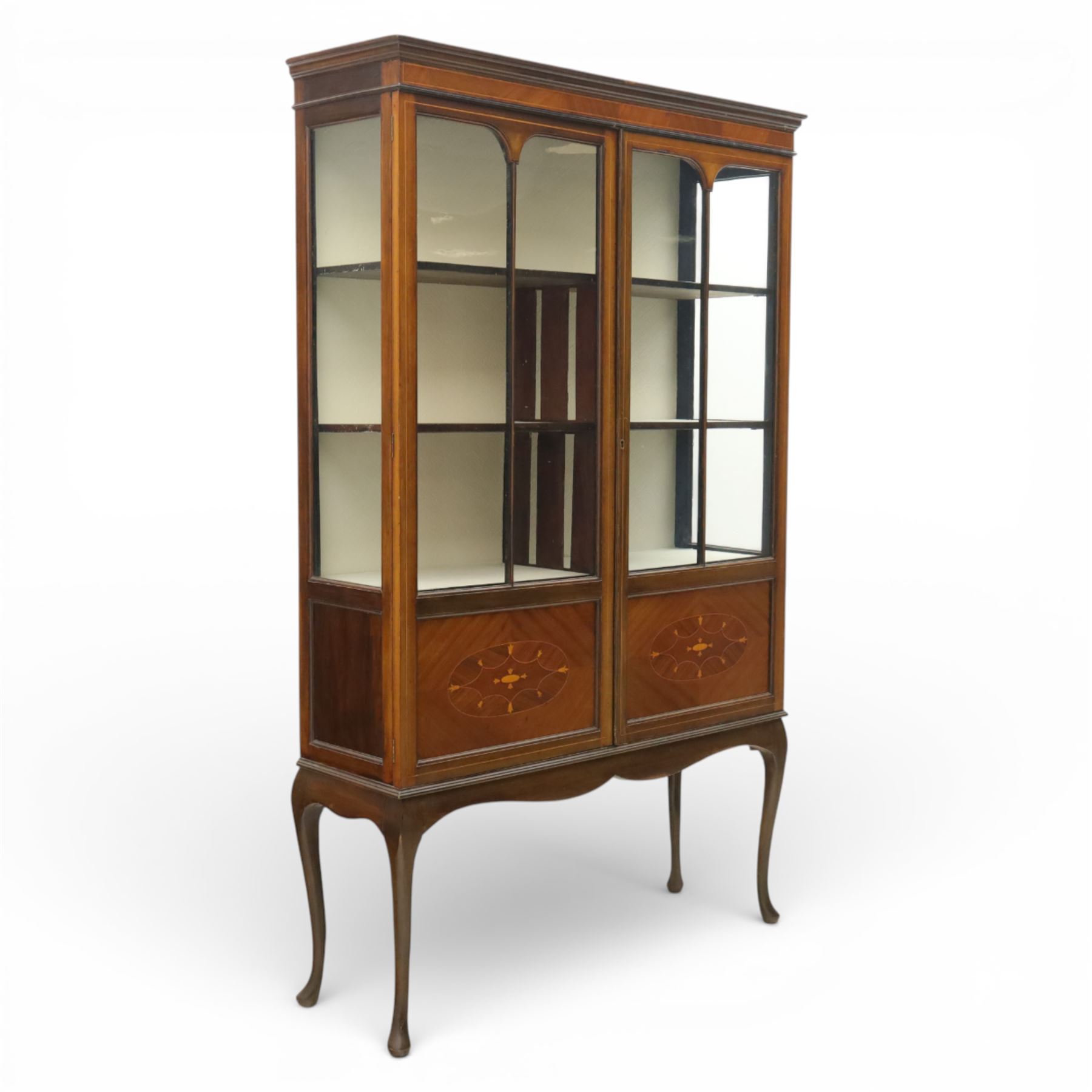 20th century Edwardian style mahogany display bookcase cabinet, the moulded cornice above two lancet glazed doors enclosing a shelved interior, the lower sections with oval inlaid fan decoration, supported on shaped cabriole legs