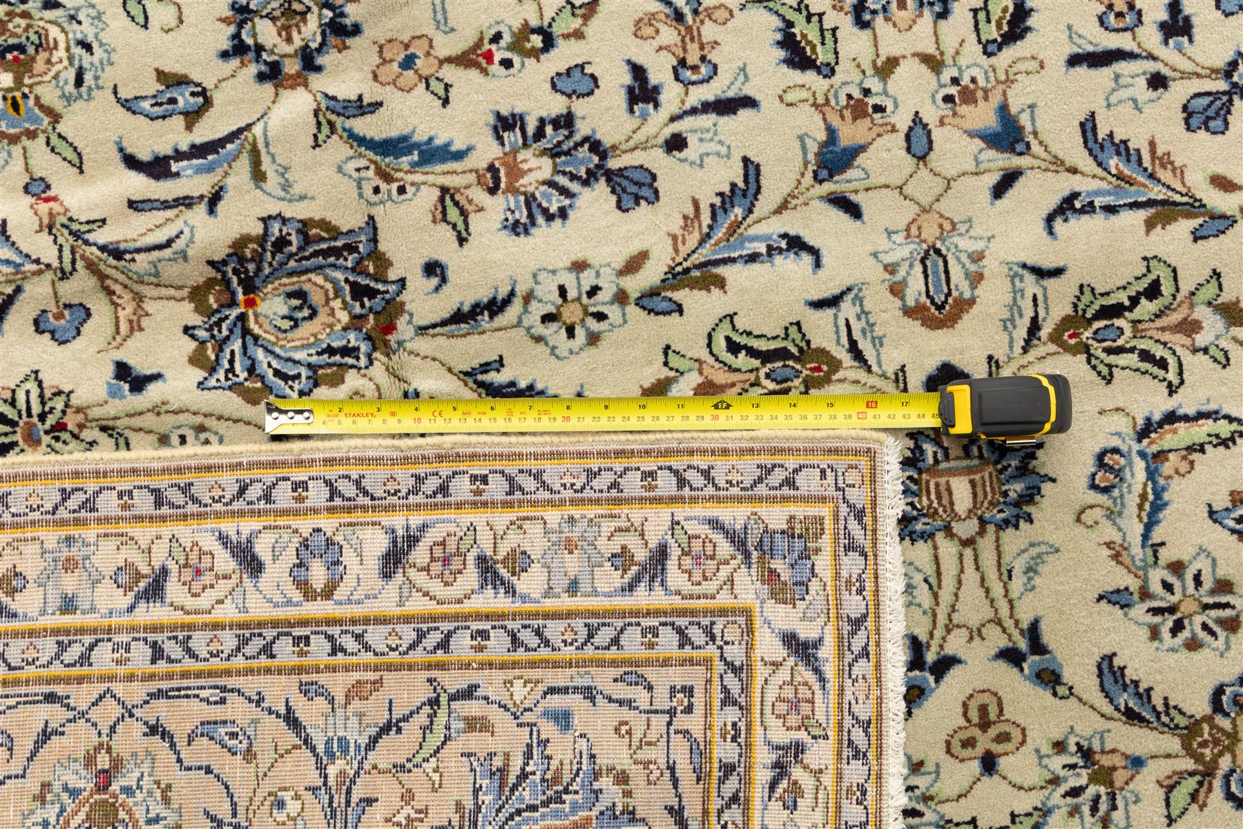 Central Persian Kashan hand-knotted rug, ivory field intricately decorated with an all-over design of scrolling vines, palmettes, and stylized lotus motifs in shades of soft blue, pale gold, and indigo within floral borders