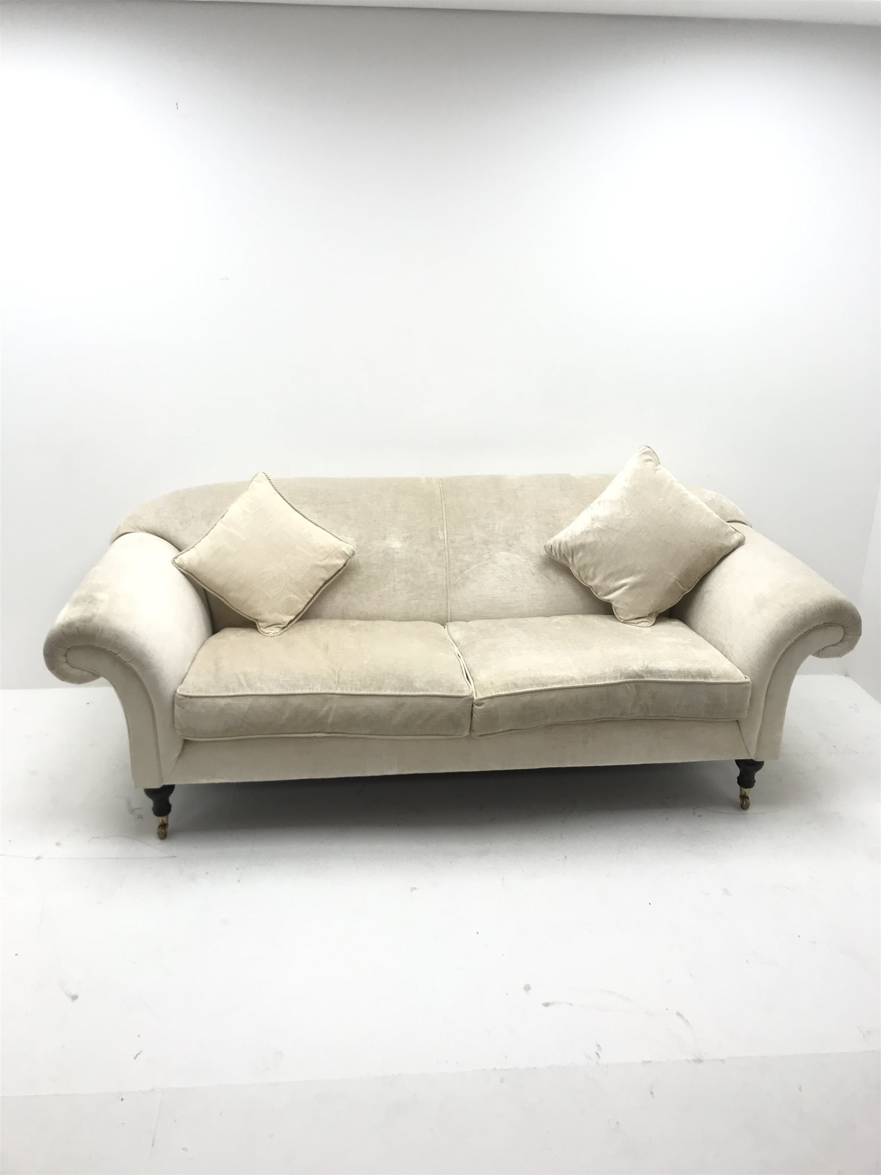 Three seat sofa upholstered in an cream chenille fabric, scrolled arms, turned supports, W220cm