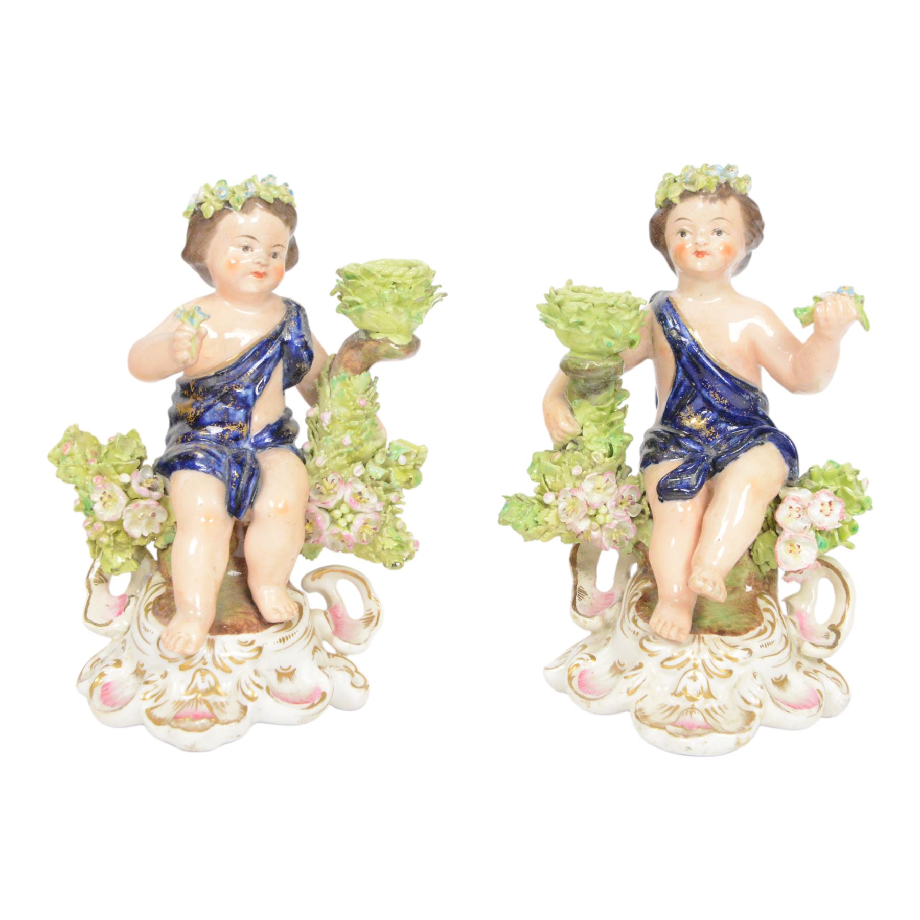 Pair of 19th century Stevenson and Hancock Derby figural chambersticks, each modelled as a seated cherub with arm around foliate encrusted sconce, marked beneath, H18cm