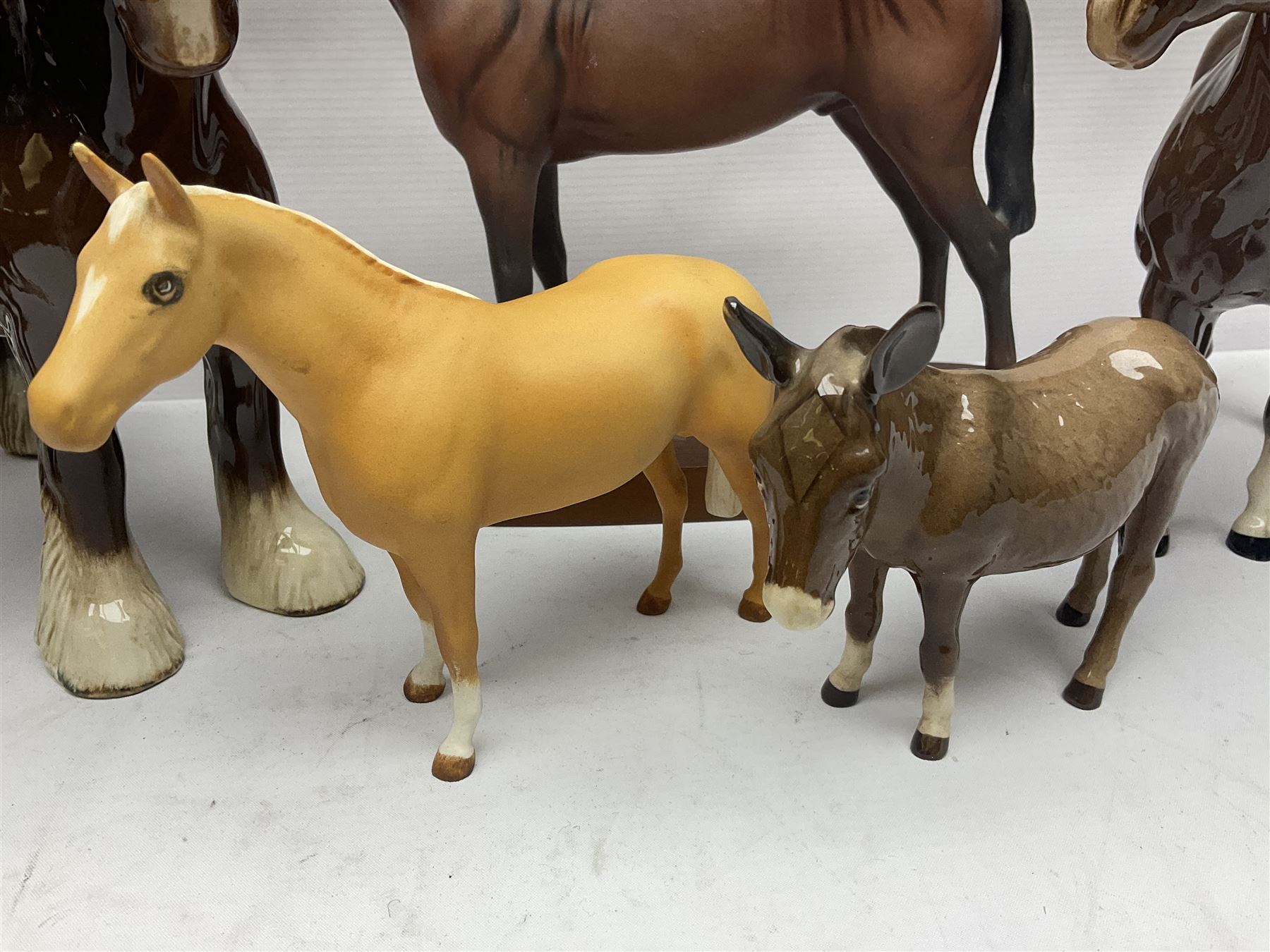 Four Beswick horse figures, comprising Quarter Horse, two Shires no 818 and matt palomino, together with Beswick donkey and Royal Doulton horse on a wooden plinth  