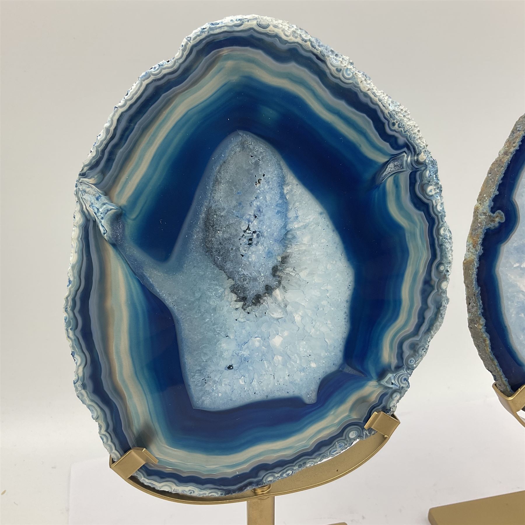 Pair of blue agate slices, polished with rough edges raised upon gilt metal stands, H22cm