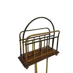 Edwardian oak and brass revolving magazine stand, arched frame with slatted slides and oak base, mounted on a brass column supported by three stylized scrolling legs terminating in pad feet