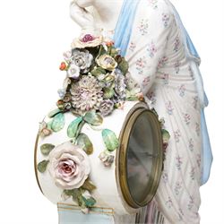 Large19th century  German porcelain mantel clock with white dial and striking movement, the case with a standing figure of Flora resting on a pillar with floral applied decoration, the base painted eith landscape and floral panels on paw feet H77cm W43cm