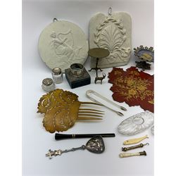 A group of assorted collectables, to include silver mounted box with unassociated silver napkin ring, silver sugar tongs, small silver mounted glass pot, silver pendant, pounce pot, pair of glass inkwells, Victorian mesh purse, Victorian papier lacquer fan, two Neoclassical type plaster plaques, novelty brass tilt top table, cheroot holder, bone handled seal, bone counter in the form of a fish, etc. 