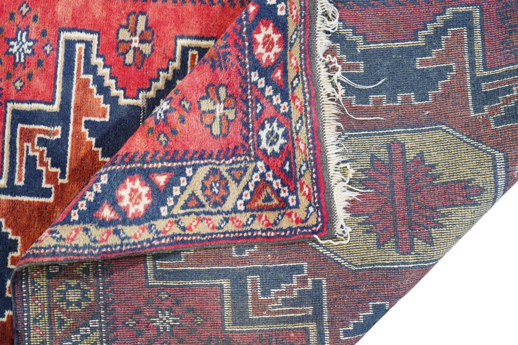 Caucasian pale red ground rug, the field decorated with three large medallions and stylised flower heads, within repeating border 