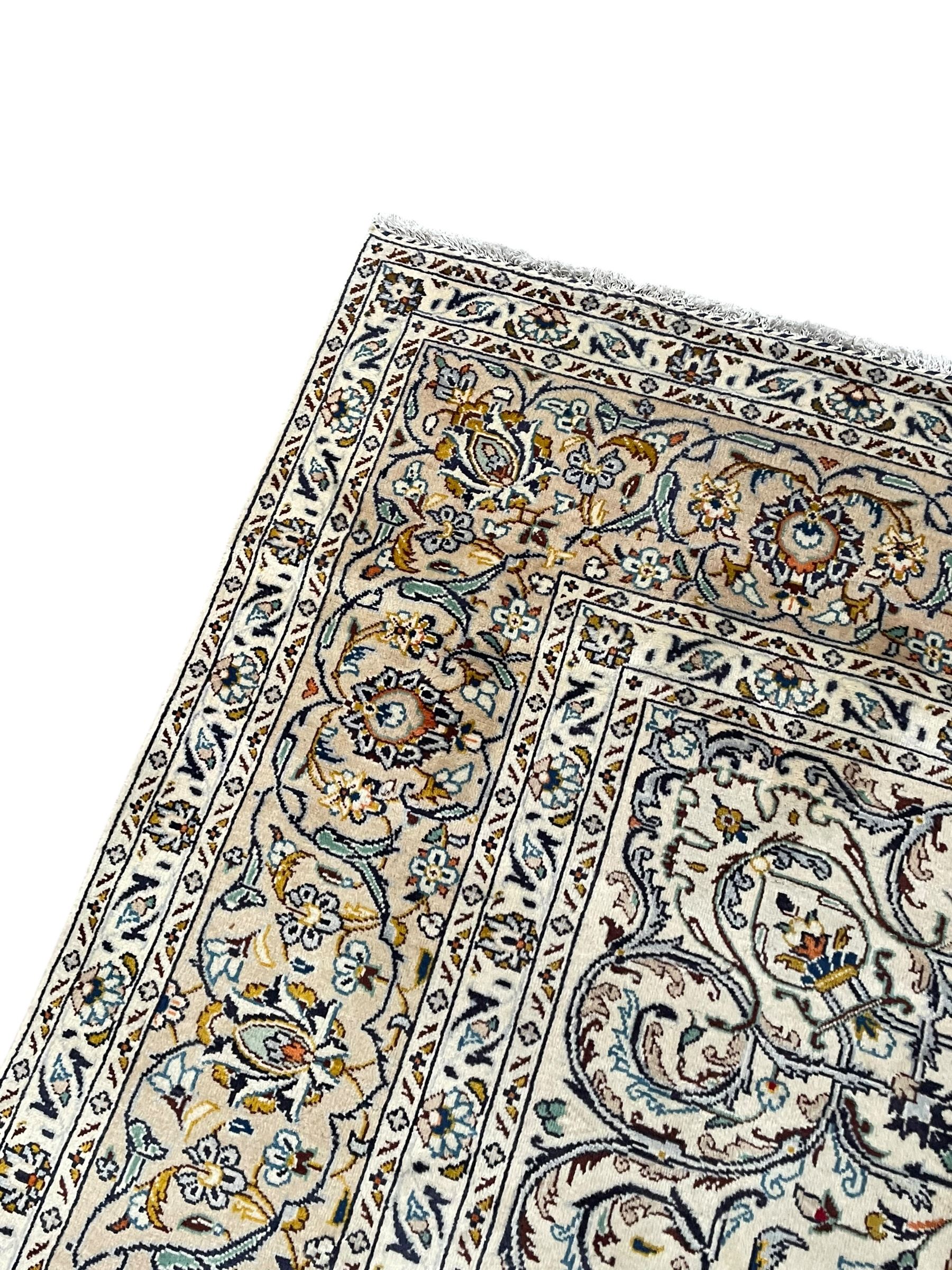 Persian Kashan ivory ground carpet, central pole medallion surrounded by swirling leafy branches and stylised plant motifs, scrolled foliate spandrels, the main border decorated with scrolling pattern and repeating palmettes, within floral patter guard stripes 