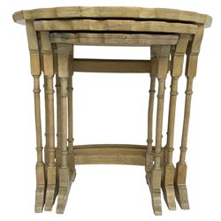 Mid 20th century bleached walnut nest of three tables, oval piecrust tops on turned supports