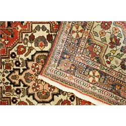 Persian Heriz-style rug, bold geometric octagonal medallion, rich red field with ivory spandrels, dark navy border, rosettes and vines; inner guards with repeating patterns 