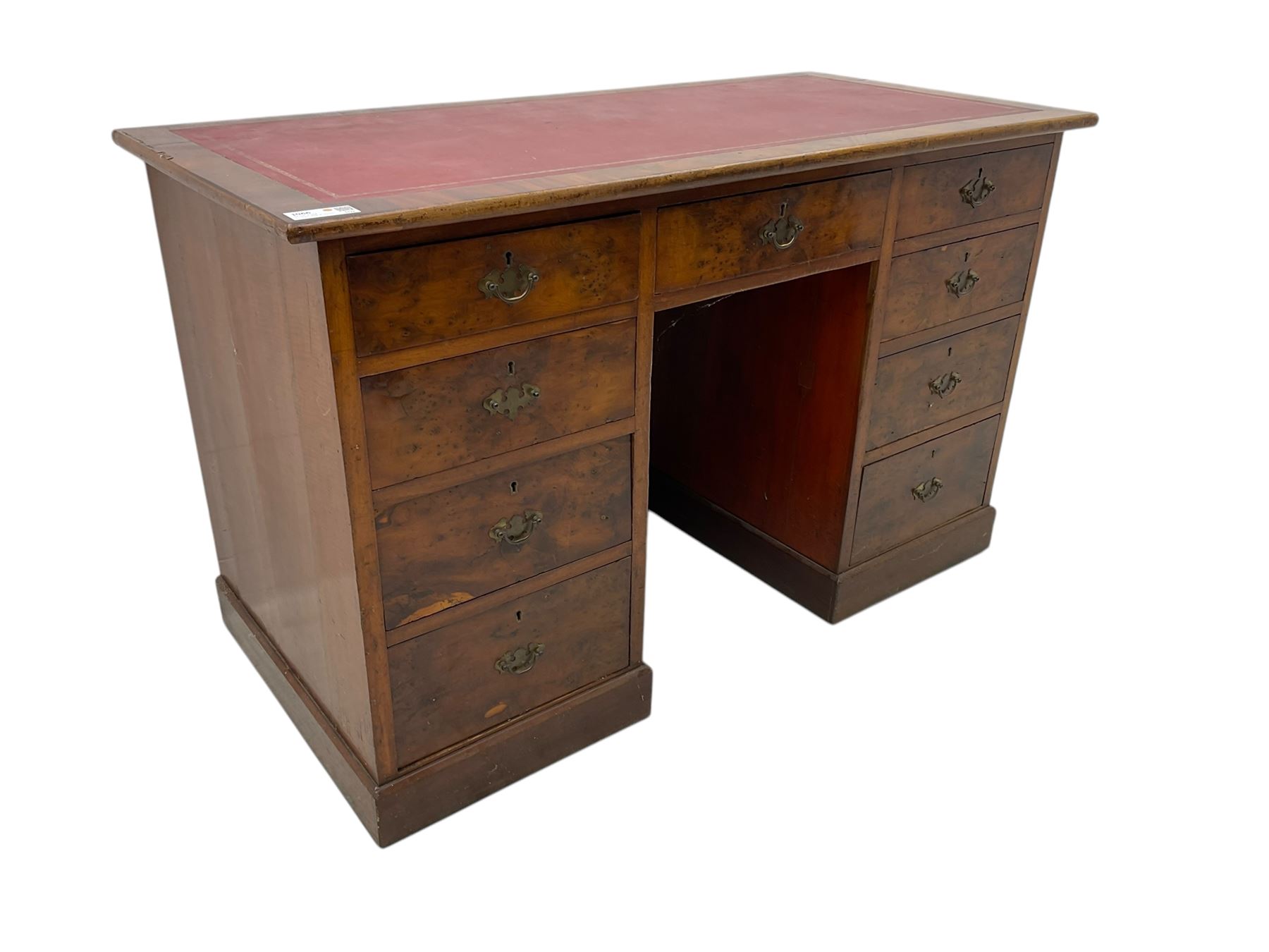 Late 19th to early 20th century walnut pedestal desk, rectangular top inset with red tooled leather writing surface, over a central frieze drawer flanked by two pedestals, each fitted with four graduated drawers with brass escutcheons and drop handles, the whole raised on a plinth base