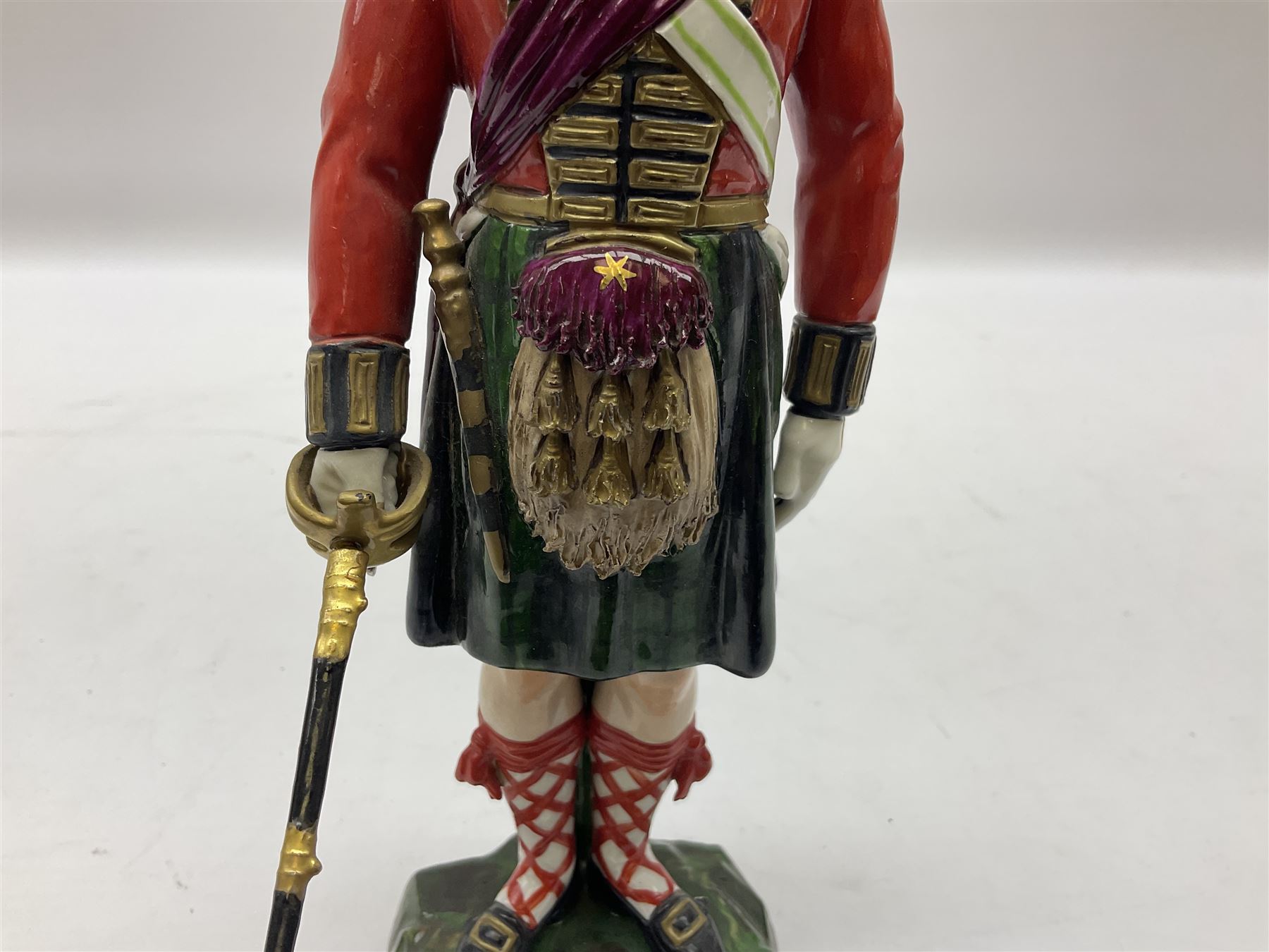 Sitzendorf figure, The Black Watch officer, c1815 standing to attention in full dress with sword, blue factory marks beneath, H28cm