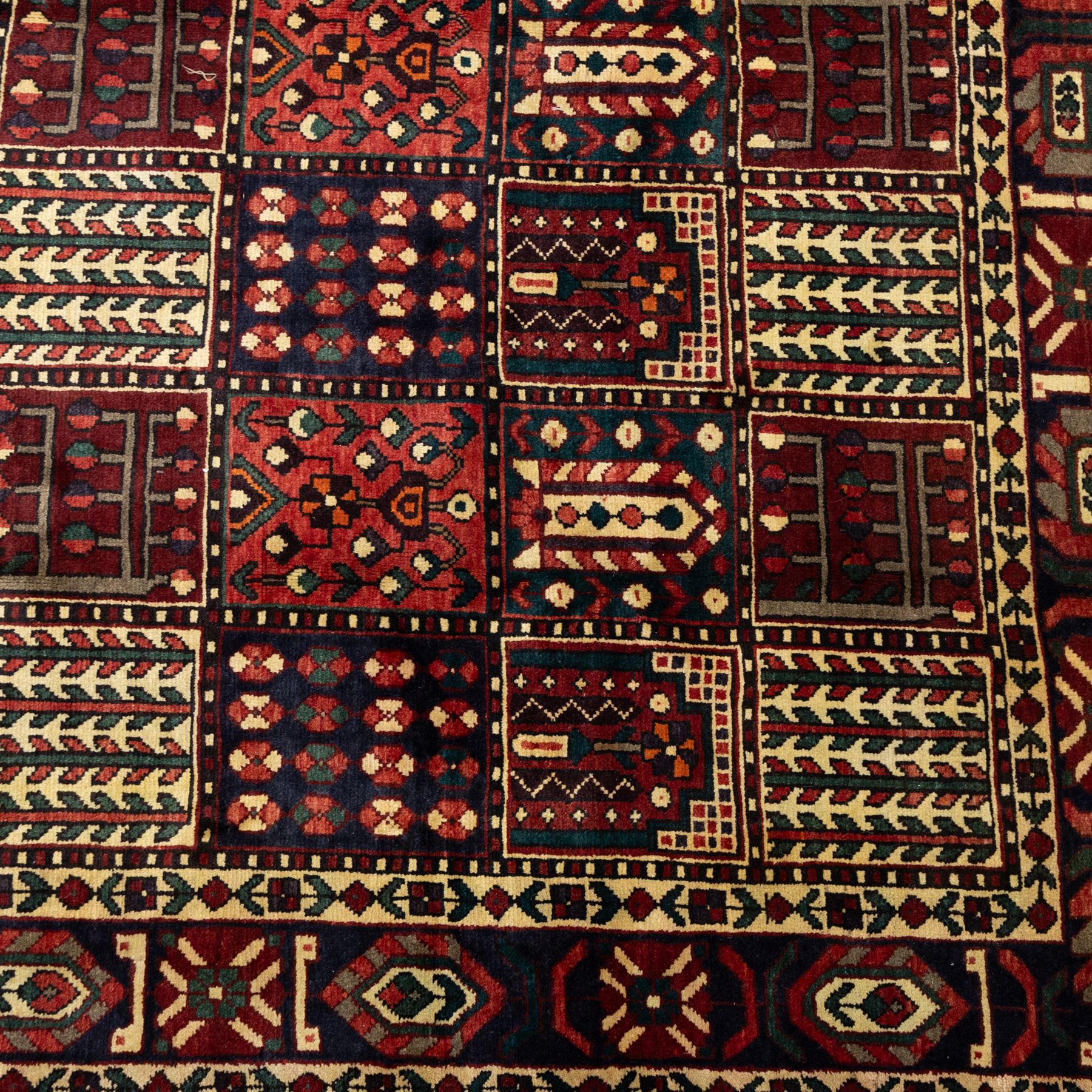 Bakhtiari wool rug, compartmented garden design field with panels of stylised trees, flowers and geometric motifs, enclosed by dark blue main border with repeating floral medallions and guard stripes