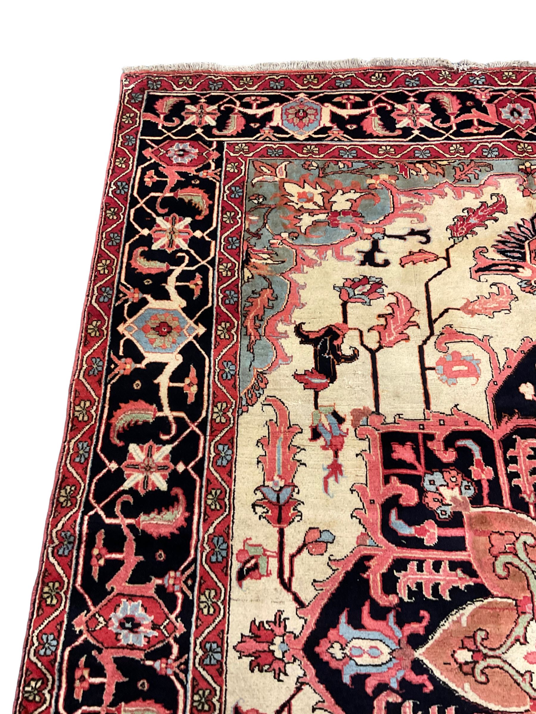 North West Persian Heriz carpet, ivory ground with large central medallion and floral spandrels, triple band border with scrolling design decorated with flower head and plant motifs 
