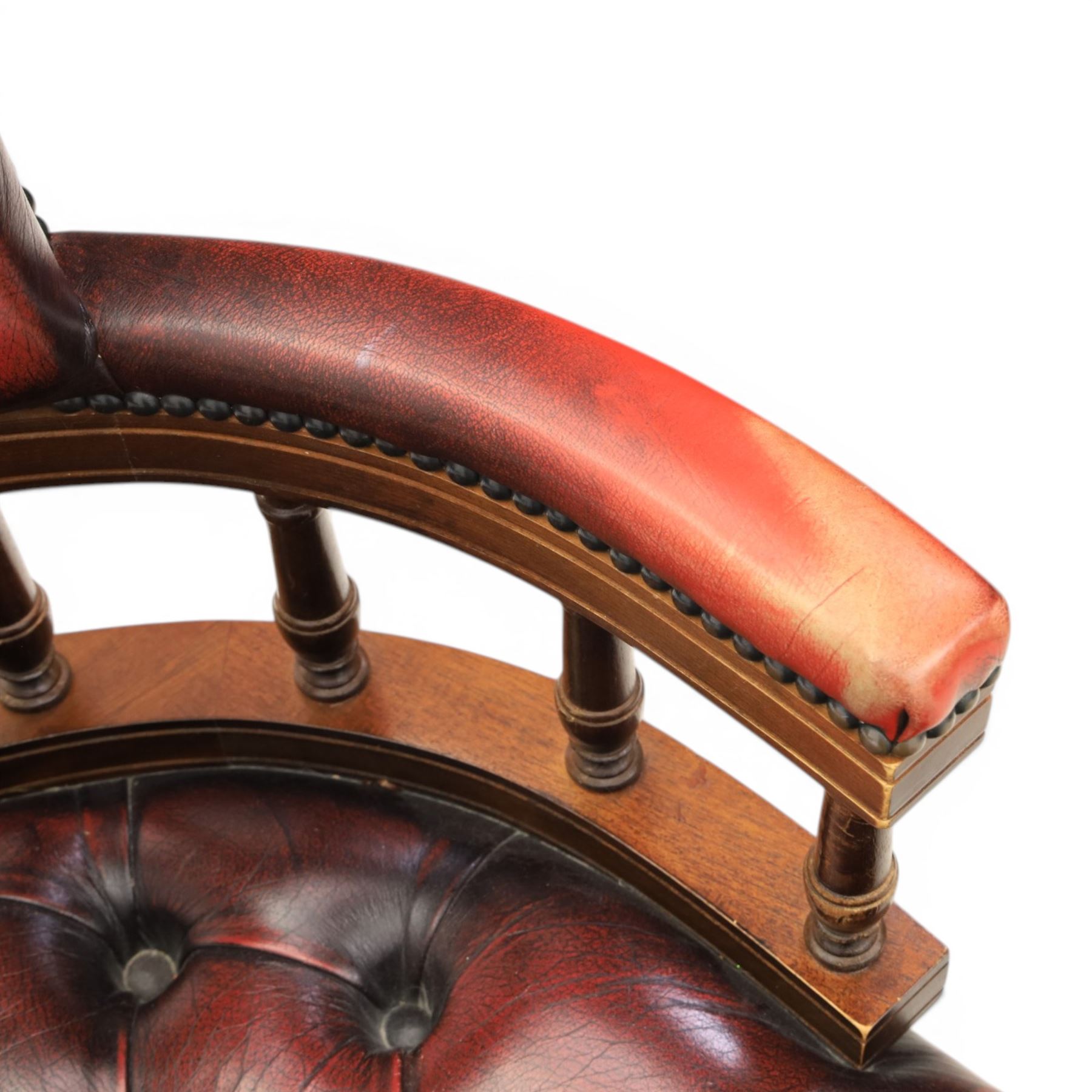 Captains swivel desk chair upholstered in oxblood leather, buttoned back and seat, shaped arm bow raised on turned spindles, five spoke base raised on castors