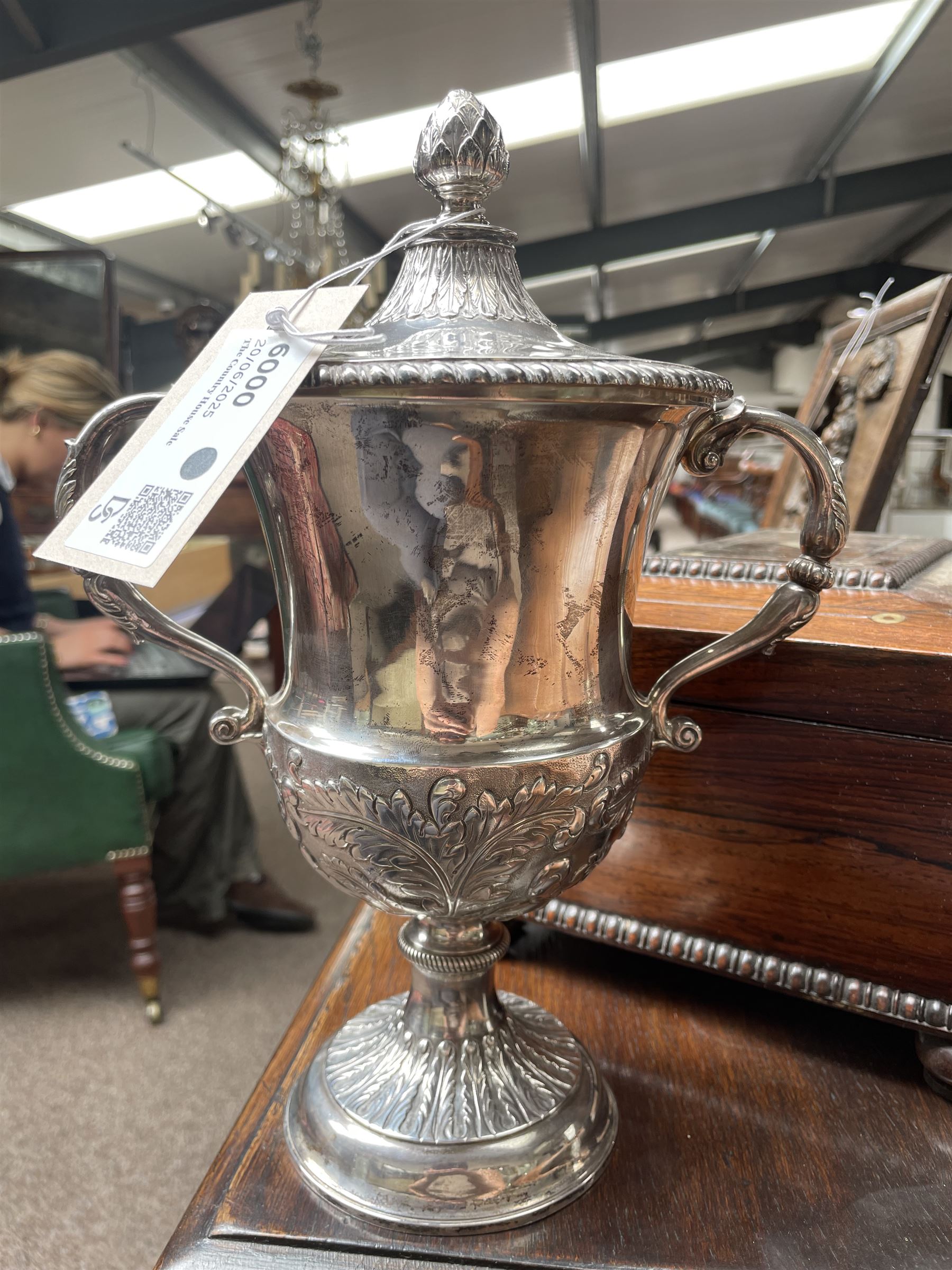 George III silver two handled campana shape cup and cover with pineapple lift, the body with cartouche surrounded by flowers above leaves and scrolls on a pedestal foot with acanthus leaf decoration H29cm London 1764, makers marks rubbed