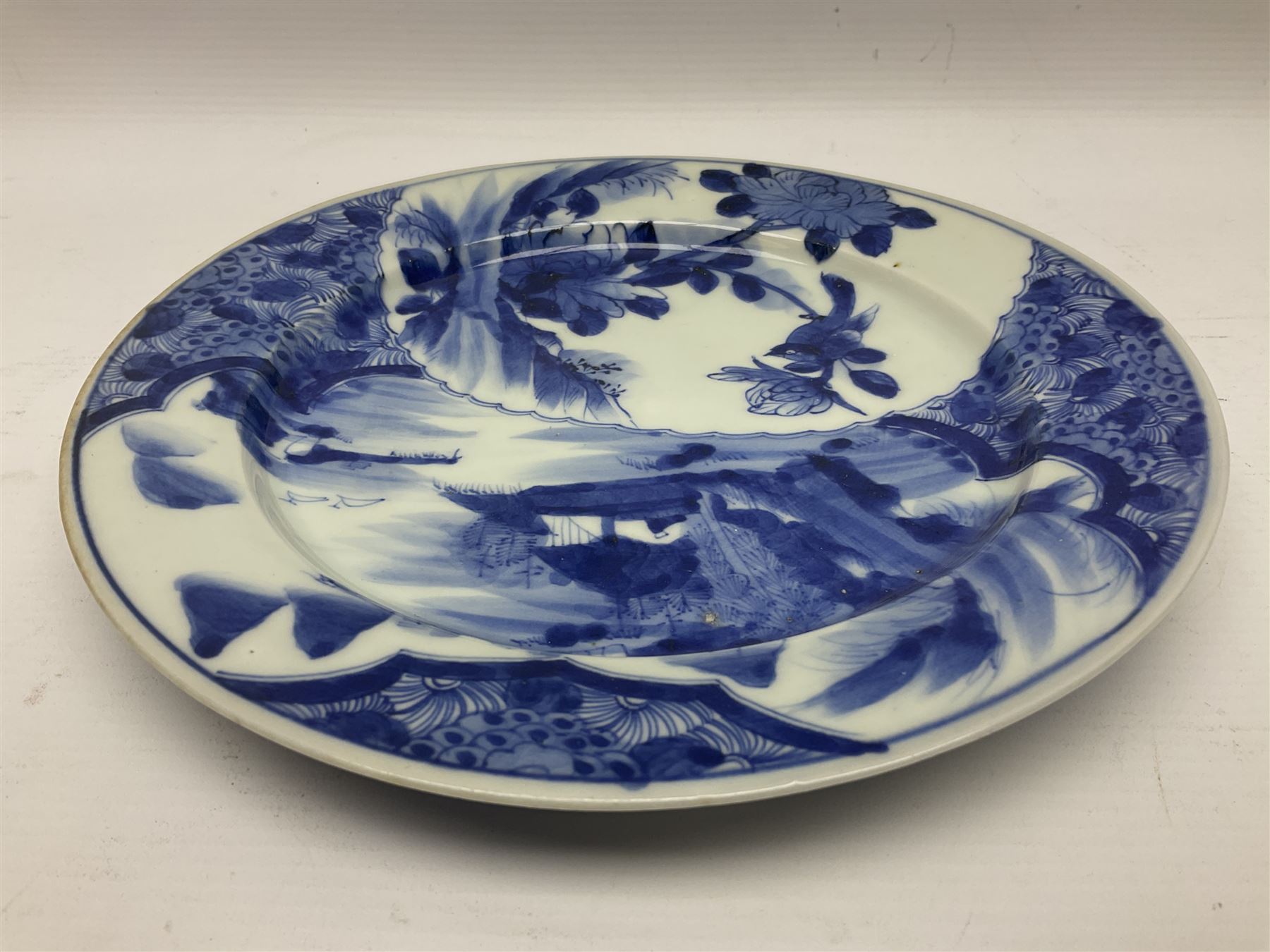 Japanese Meiji period Arita blue and white plate, of circular form, painted with riverside landscape and bird upon flowering branch, with character mark beneath, D24.5cm, together with two 18th century Chinese blue and white plates, each painted with floral design, each approximately D22.5cm