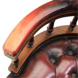 Captains swivel desk chair upholstered in oxblood leather, buttoned back and seat, shaped arm bow raised on turned spindles, five spoke base raised on castors