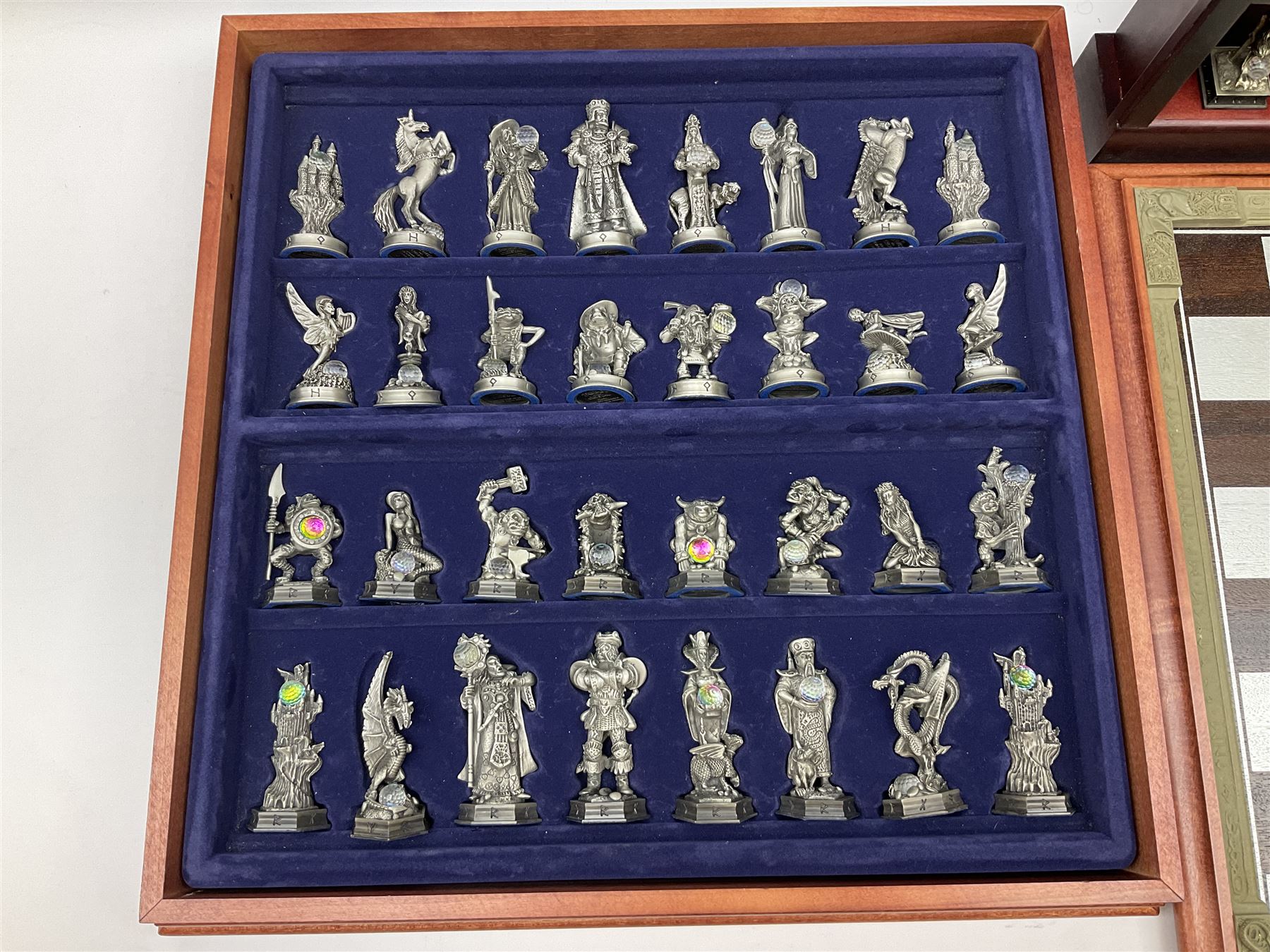 Danbury Mint 'The Fantasy of the Crystal' chess set consisting of mythical pewter chess pieces within a wooden case with chess board lid, together with 16 additional chess pieces in a wooden display case.