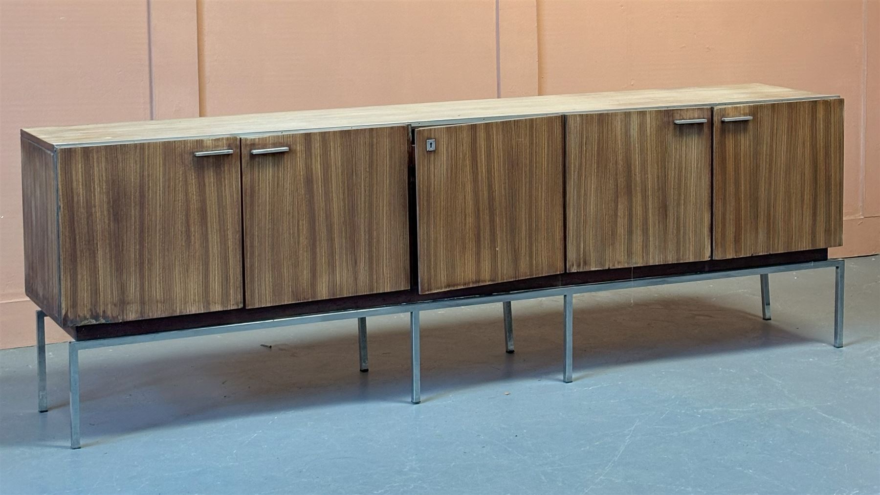 Large Italian teak veneered sideboard, circa 1960's, fitted with five drawers enclosing a birds eye maple lined interior fitted with shelves, raised on a chrome plated box section base. Water damage to doors and sides. H80cm, L245cm, D48cm  - COLLECTION BY APPOINTMENT FROM: The White House, Thirsk Road, Easingwold, York, YO61 3NF - CALL 01723 507111 TO ARRANGE