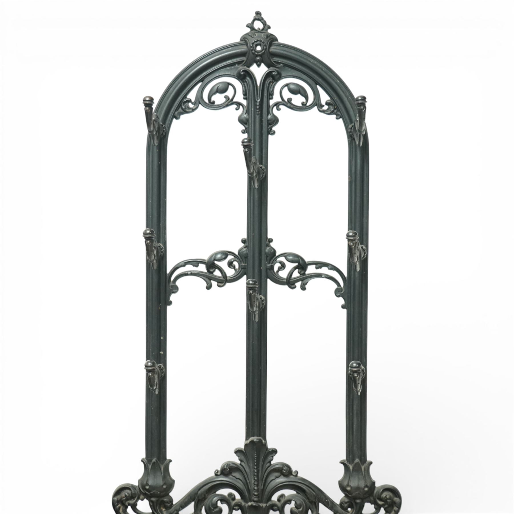 Late 19th century cast iron stick stand, the arched back with scrolling foliate decoration, fitted with multiple hooks, the lower section with pierced panels centred by a radiating sunburst motif, raised on a rectangular drip tray base