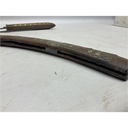Late 19th/early 20th century Moroccan nimcha dagger-sword, the 40cm curving steel blade with engraved decoration on both sides; shaped hardwood hilt inlaid with brass, white metal wires and red coloured panels; in similarly inlaid scabbard L61cm overall